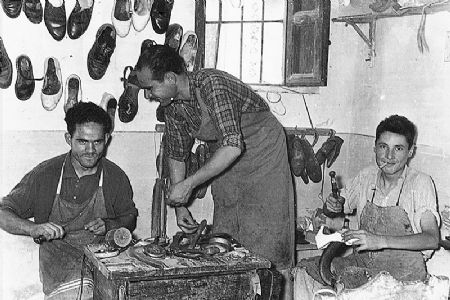Taller de zapatería. Obrero de reparación de zapatos. Foto del año 1956.